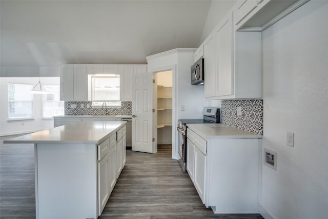 kitchen with appliances with stainless steel finishes, white cabinets, light countertops, and a center island