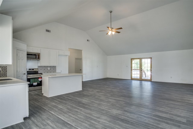 kitchen featuring stainless steel appliances, light countertops, open floor plan, and white cabinets