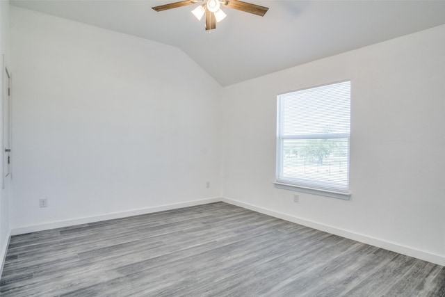 unfurnished room featuring light wood-type flooring, ceiling fan, baseboards, and vaulted ceiling