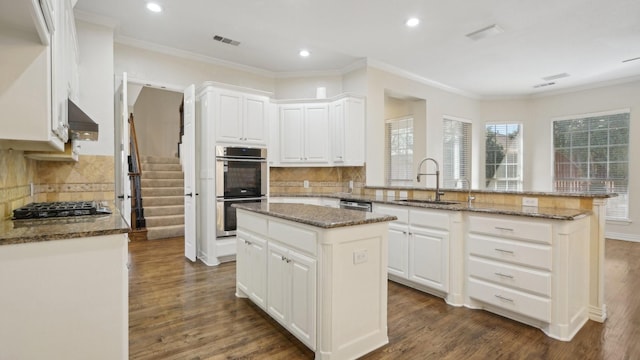 kitchen featuring a sink, appliances with stainless steel finishes, a kitchen island, and white cabinetry