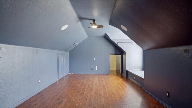 additional living space featuring a ceiling fan, a textured wall, lofted ceiling, wood finished floors, and a textured ceiling