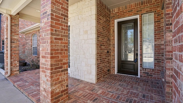 view of exterior entry featuring brick siding