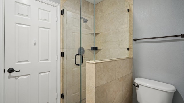 bathroom with toilet, a stall shower, and a textured wall