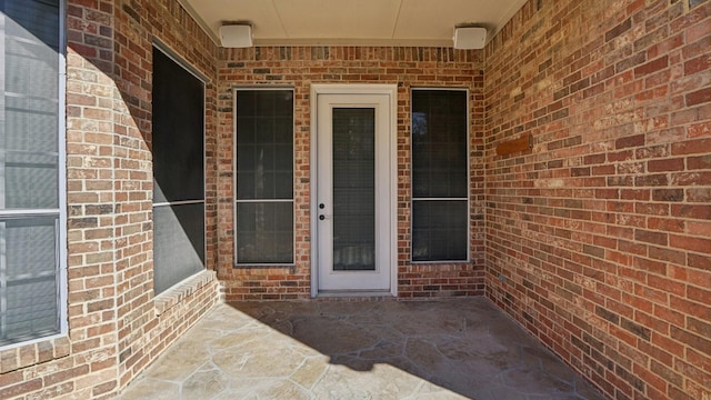 entrance to property with a patio and brick siding