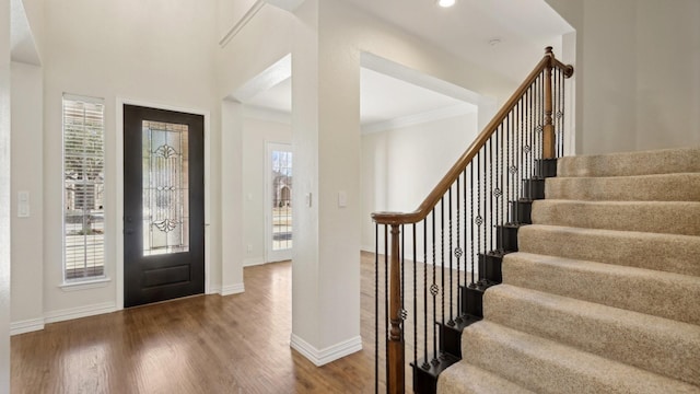 entryway featuring crown molding, a wealth of natural light, dark wood finished floors, and baseboards