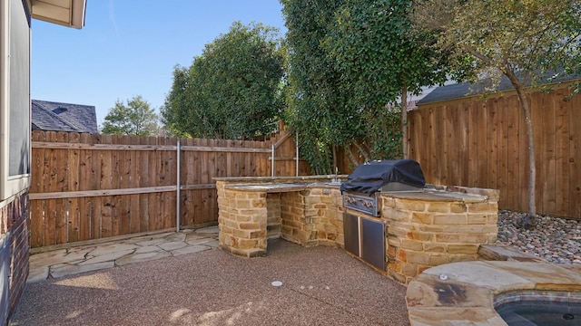 view of patio with area for grilling, an outdoor kitchen, and fence