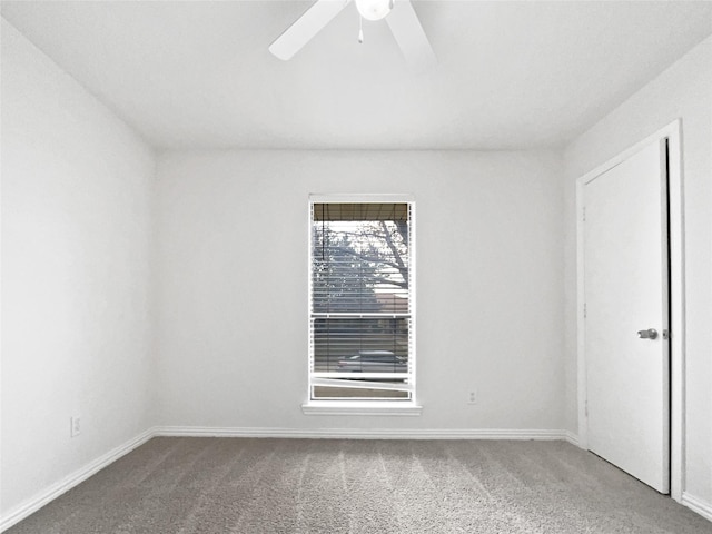 carpeted spare room featuring ceiling fan and baseboards