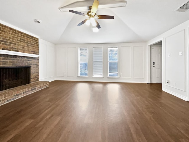 unfurnished living room with vaulted ceiling, a fireplace, visible vents, and a decorative wall