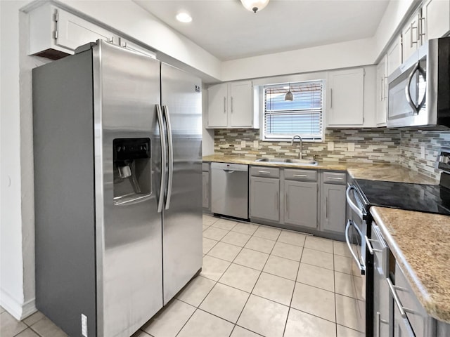 kitchen with light tile patterned floors, stainless steel appliances, a sink, light countertops, and tasteful backsplash