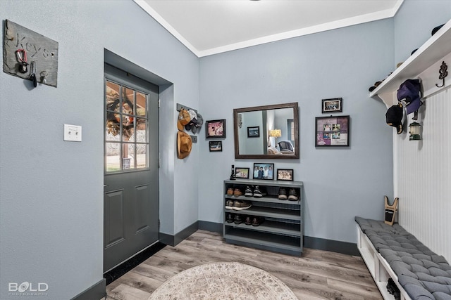 entrance foyer with ornamental molding, wood finished floors, and baseboards