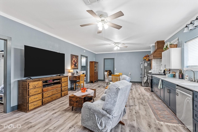 living area featuring visible vents, a ceiling fan, baseboards, ornamental molding, and light wood-type flooring