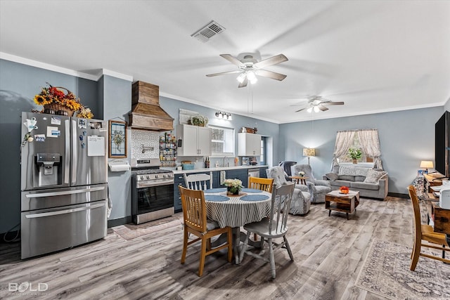 dining space with light wood-style flooring, visible vents, baseboards, a ceiling fan, and ornamental molding