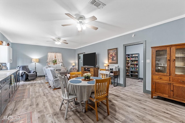 dining room with baseboards, visible vents, crown molding, and light wood finished floors