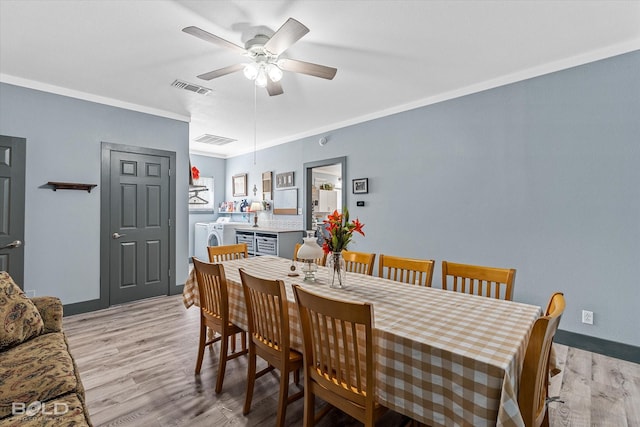 dining space featuring visible vents, crown molding, washer and clothes dryer, and light wood finished floors