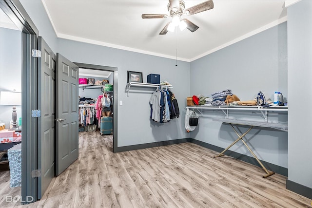 interior space featuring baseboards, ceiling fan, light wood-type flooring, and crown molding