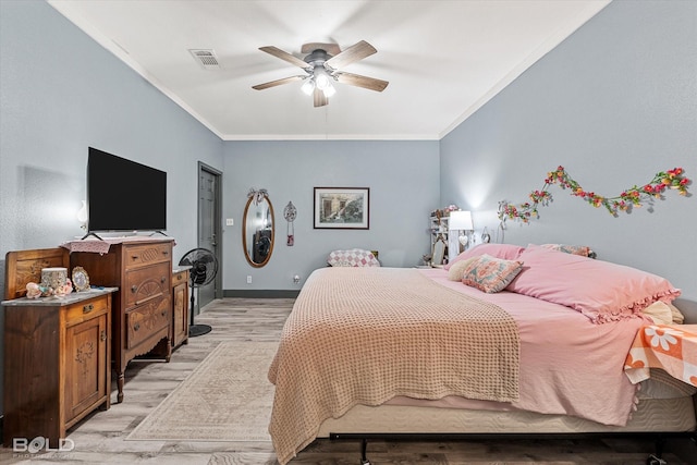 bedroom with baseboards, light wood-style flooring, visible vents, and crown molding