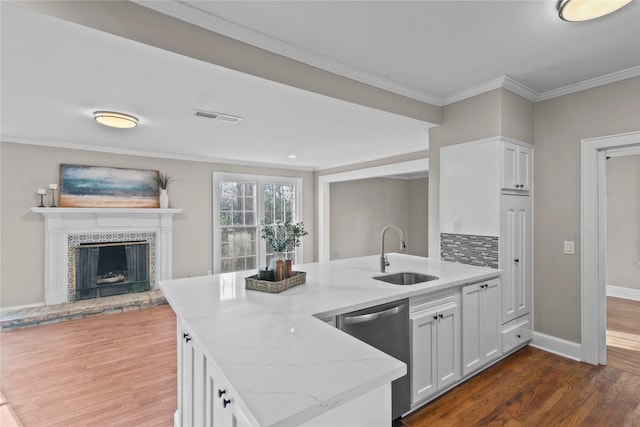 kitchen with visible vents, a tiled fireplace, light stone counters, stainless steel dishwasher, and a sink