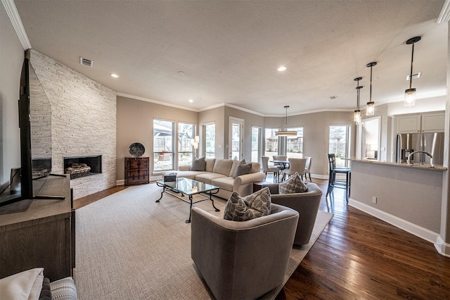 living area with dark wood-style flooring, a fireplace, visible vents, and crown molding