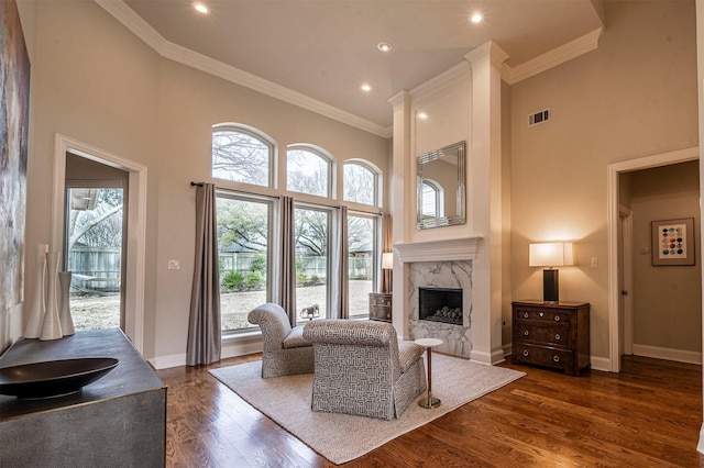 living area with dark wood-type flooring, a fireplace, a towering ceiling, and visible vents