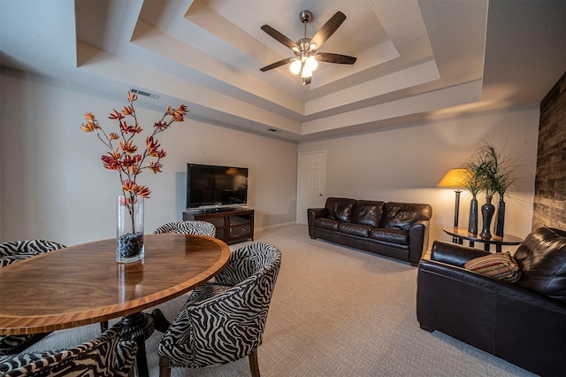 carpeted living area featuring visible vents, a tray ceiling, and a ceiling fan