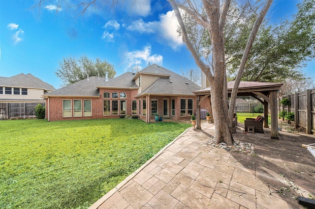 back of property featuring brick siding, a lawn, a gazebo, a patio area, and a fenced backyard