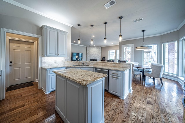 kitchen featuring a peninsula, visible vents, dark wood-type flooring, and a sink