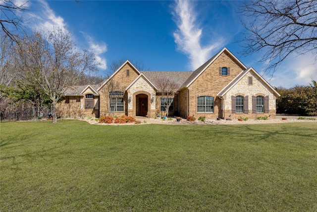 french country inspired facade featuring brick siding and a front yard