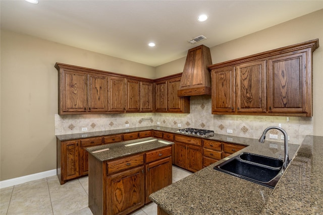 kitchen with visible vents, a sink, custom range hood, stainless steel gas stovetop, and backsplash