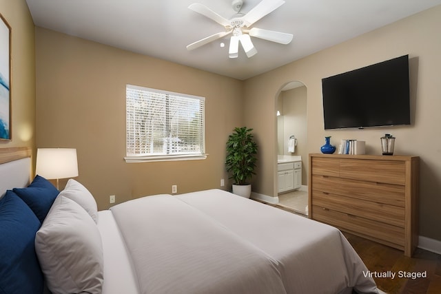 bedroom featuring a ceiling fan, ensuite bath, light wood-style floors, and baseboards