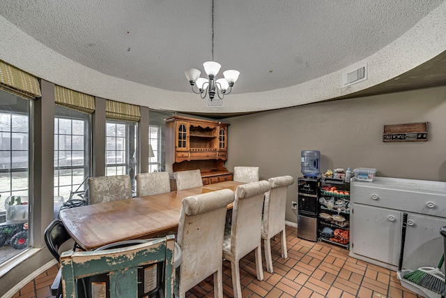 dining space featuring baseboards, visible vents, brick floor, a textured ceiling, and a chandelier