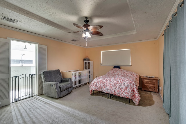 carpeted bedroom featuring a tray ceiling, visible vents, crown molding, and a textured ceiling