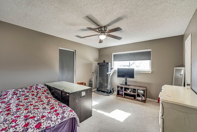 bedroom featuring a ceiling fan, visible vents, light carpet, and a textured ceiling