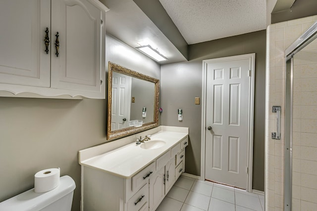 bathroom featuring a textured ceiling, tile patterned flooring, toilet, vanity, and a tile shower