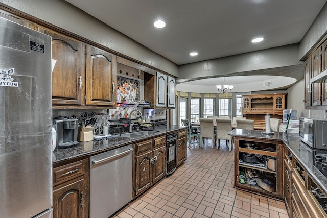 kitchen with decorative light fixtures, brick floor, stainless steel appliances, a sink, and recessed lighting