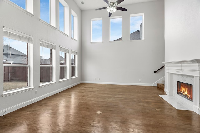 unfurnished living room with baseboards, a ceiling fan, dark wood-style floors, stairway, and a fireplace