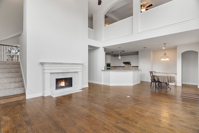 unfurnished living room featuring a fireplace, stairway, baseboards, and wood finished floors