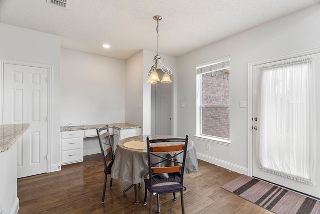 dining space featuring a healthy amount of sunlight, a textured ceiling, dark wood-type flooring, and built in study area