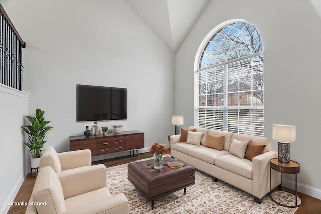 living area with high vaulted ceiling, light wood finished floors, and baseboards