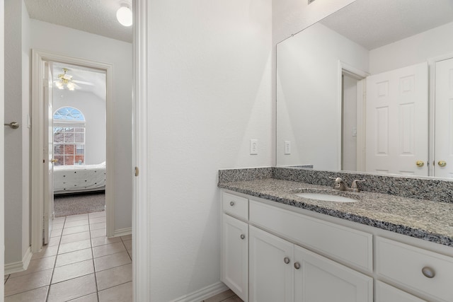 ensuite bathroom featuring ensuite bathroom, a textured ceiling, vanity, tile patterned flooring, and baseboards