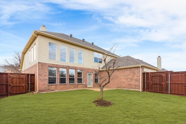 rear view of house featuring a chimney, a gate, fence, a yard, and brick siding