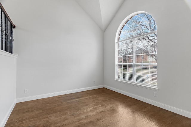 empty room with vaulted ceiling, wood finished floors, and baseboards