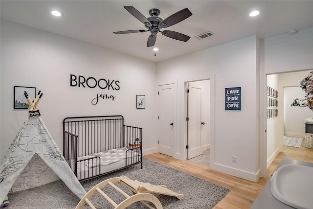 bedroom with a sink, wood finished floors, visible vents, and recessed lighting