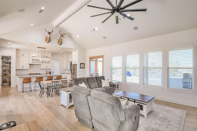 living area featuring a ceiling fan, light wood-style flooring, beamed ceiling, french doors, and high vaulted ceiling