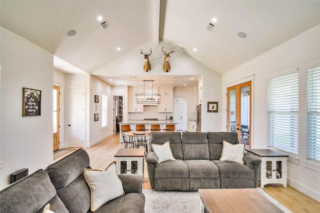 living room with light wood-style floors, french doors, visible vents, and vaulted ceiling with beams