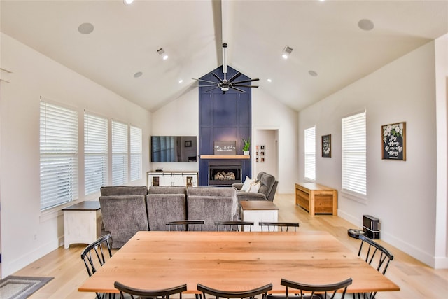 dining room with ceiling fan, high vaulted ceiling, a fireplace, visible vents, and light wood-style floors