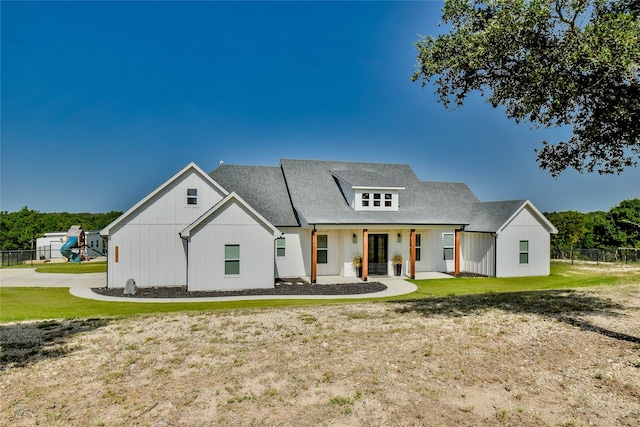 modern inspired farmhouse with a playground, a shingled roof, board and batten siding, fence, and a front lawn