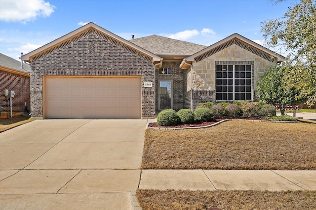 view of front of property featuring concrete driveway, stone siding, roof with shingles, an attached garage, and brick siding