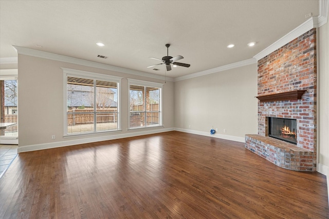 unfurnished living room featuring wood finished floors, visible vents, baseboards, a brick fireplace, and crown molding