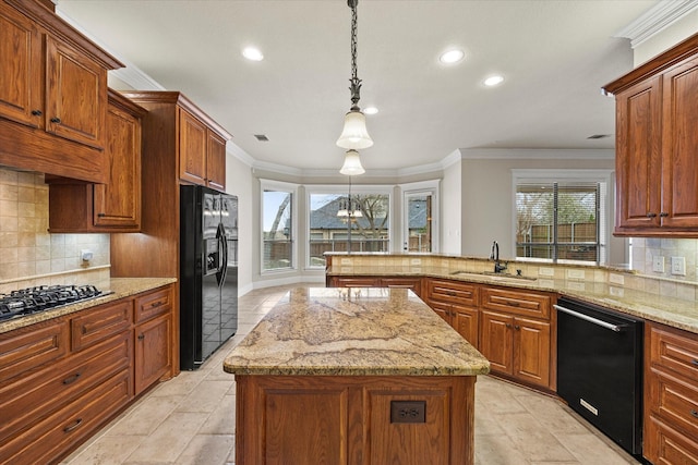 kitchen featuring a center island, crown molding, black appliances, pendant lighting, and a sink