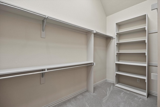 spacious closet featuring lofted ceiling and dark carpet